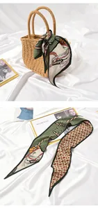 Close-up detail of pleated silk scarf with horse pattern elegantly tied to a woven straw bag.