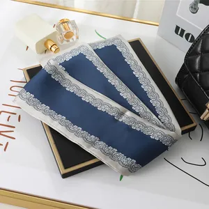 Close-up detail of dark blue satin neckerchief with elegant white lace border print