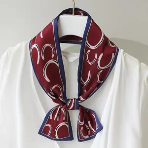 Detail of retro wine red skinny scarf with white horseshoe pattern tied in a bow