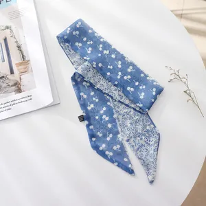 Close-up detail of a blue French vintage floral skinny scarf on a white table