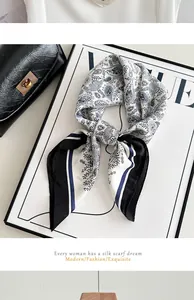 Detail shot of a blue and white paisley pattern silk scarf tied in a sophisticated knot.