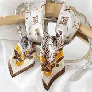 Close-up of elegant silk square scarf with vintage feather and belt pattern