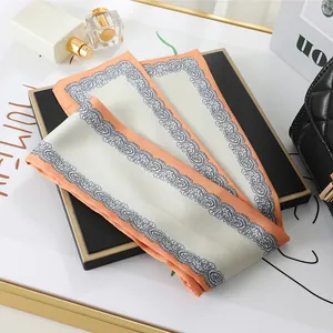 Close-up of a stylish cream and orange satin scarf featuring an elegant lace pattern design.
