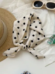 Close-up of a retro cream cotton linen square scarf with black polka dots tied in a knot