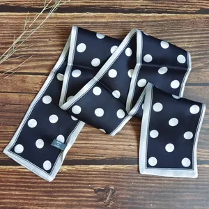 Close-up detail of a retro French style polka dot skinny scarf on wood surface.