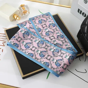 Close-up detail of pink satin neck scarf featuring crowned bird print and blue border
