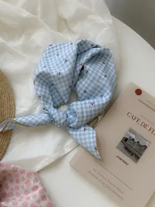 Close-up of blue checkered neckerchief with cherry pattern on white fabric