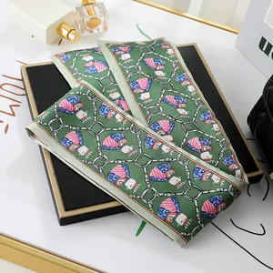 Close-up of luxury green silk scarf with elegant crown bird and silver chain print