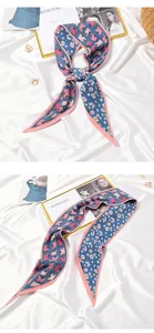 Detailed view of blue pleated scarf with pink floral and handbag pattern motifs