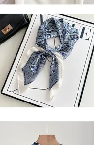 Detail shot of blue and white paisley silk scarf tied in an elegant bow on a prop board.