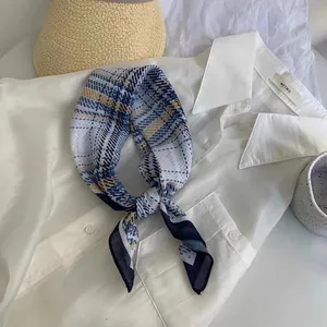 Vista dettagliata di un foulard di seta a quadri blu e gialli annodato sopra un colletto bianco.
