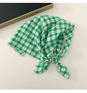Close-up detail of a green gingham cotton linen square scarf with small floral patterns.