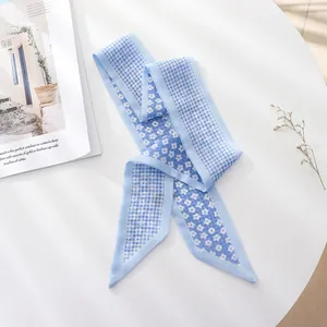 Close-up of blue floral and checkered chiffon hair scarf on a minimalist white table