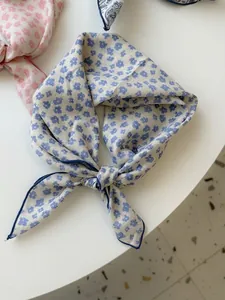 Detailed close-up of a blue floral cotton linen square scarf with tied knot decoration