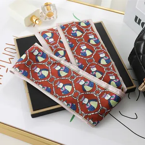 Detailed view of a long satin scarf with bird and chain pattern for bag styling