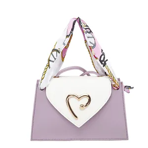 Detail of mini square bag with golden heart buckle and silk scarf handle