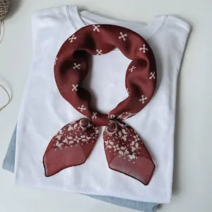 Dettaglio di un foulard in seta bordeaux con stampa floreale su una maglietta bianca