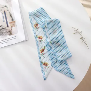 Floral and polka dot chiffon hair scarf detail shown on a white table with a magazine.