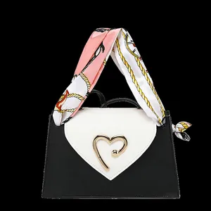 Close-up of mini square bag with golden heart buckle and colorful silk scarf handle