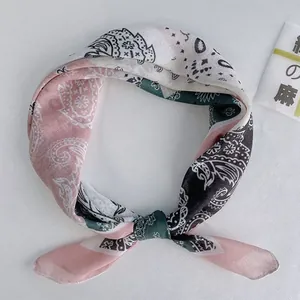 Primo piano di un foulard con stampa floreale e dettagli paisley rosa e verde ottanio