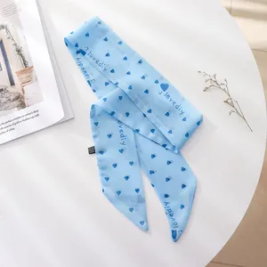 Close-up of light blue chiffon skinny scarf with navy heart pattern for hair styling