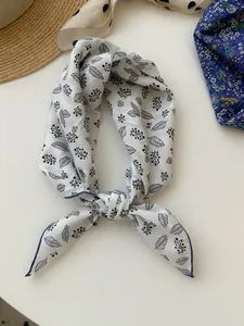 Close-up of cotton linen bandana with black floral print and blue hem border