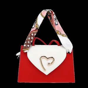 Detailed close-up of a red and white mini square handbag with a golden heart-shaped clasp