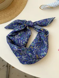 Detailed view of a purple floral cotton linen scarf tied in a decorative knot