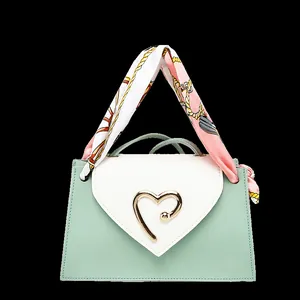 Detail of mini square handbag with heart buckle and pink scarf handle decoration