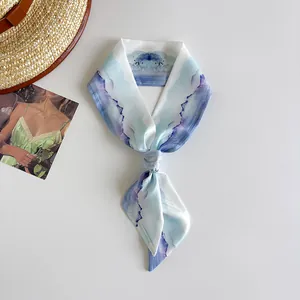 Close-up of artistic watercolor landscape silk scarf tied in a neat knot on white surface