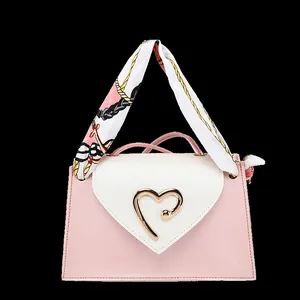 Detail of a pink mini square bag with heart-shaped gold buckle and silk scarf handle