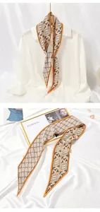 Detailed view of a pleated beige skinny scarf with orange trim and patterned design.