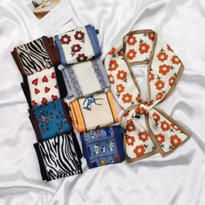 Variety of patterned skinny silk scarves displayed on white satin background