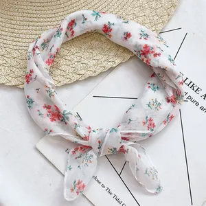 Dettaglio di un fazzoletto da collo bianco con stampa floreale annodato per l'estate.
