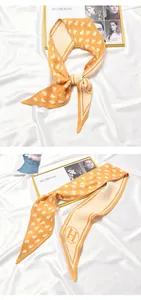 Detailed macro view of an orange pleated skinny scarf with heart patterns on white satin