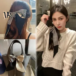 Close-up demonstration of retro houndstooth scarf used as a hair ribbon and bag accessory