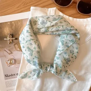 Vue détaillée d'un petit foulard à fleurs bleues noué sur un t-shirt blanc