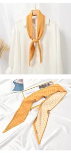 Macro detail of pleated yellow skinny scarf with white polka dots on white satin background