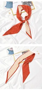 Macro view of pleated skinny silk scarf featuring vibrant orange and cream polka dots