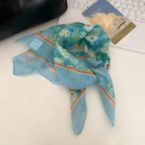 Dettaglio di un foulard in seta celeste con stampa a margherite bianche elegante