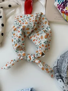 Close-up detail of a knotted cotton linen neckerchief featuring a delicate orange floral print