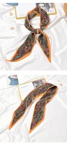 Close-up detail of an elegant orange floral pleated skinny scarf on a white silk background