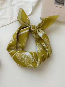 Close-up detail of retro mustard yellow cotton linen scarf with white floral pattern