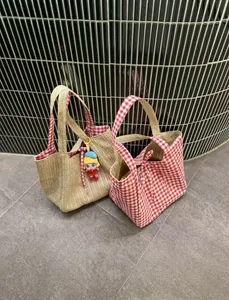 Vue détaillée de sacs cabas en paille avec doublure et extérieur à carreaux rouges