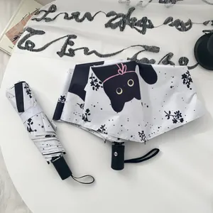 Detailed view of white automatic folding umbrella with cute black cat print and floral pattern