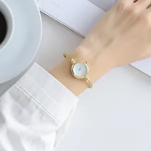 Elegant minimalist gold bangle watch for women shown worn on wrist in a clean setting