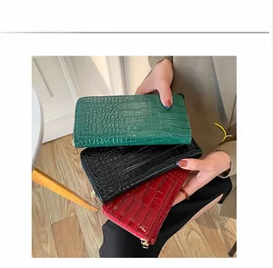 Primer plano de tres carteras largas de cuero PU con textura de cocodrilo, verde, negro, rojo