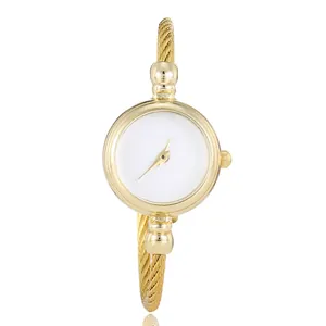 Detail shot of elegant women's gold cable strap bracelet watch with minimalist white dial
