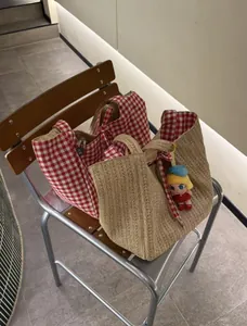 Vue détaillée des grands sacs cabas en paille tressée et à carreaux sur chaise