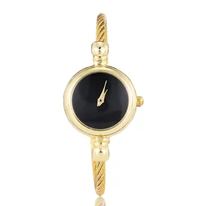 Close-up of elegant gold bangle watch with minimalist black dial and twisted band.